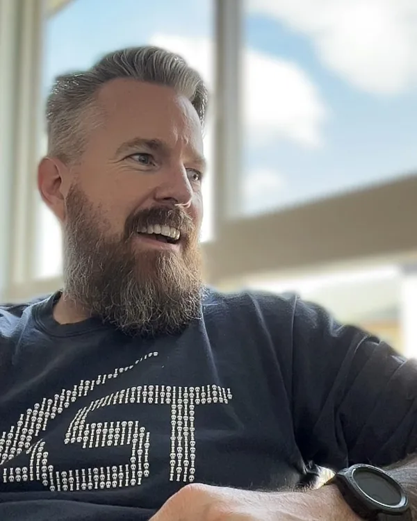 Mr. Darlin', bearded, smiling by a sunny window